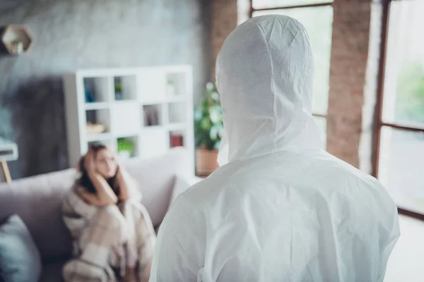 Photo of young ill patient lady lonely alone sit sofa sick look wait ambulance call visit guy doc virology clinic wear uniform protection suit hood visit her flat indoors — Stock Photo, Image