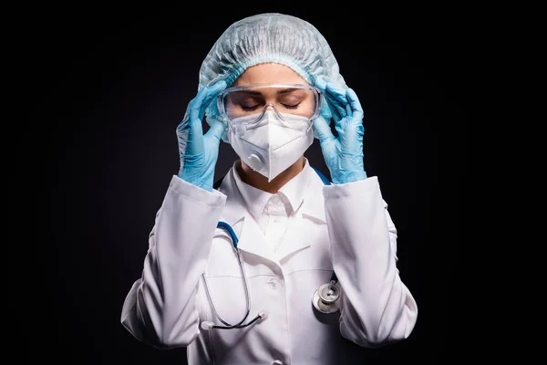 Photo of tired lady doc hold arms on protective plastic goggles rozbieranie po ostatniej operacji nosić rękawiczki maska twarz okulary specs chirurgiczne czapka odizolowany czarny kolor tło — Zdjęcie stockowe