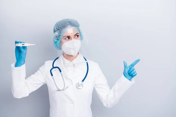 Φωτογραφία της ιολόγου της νόσου κυρία κρατήσει θερμόμετρο άμεσο δάχτυλο συμβουλεύει το κέντρο εμβολιασμού φορούν παλτό μάσκα αναπνευστήρα προσώπου πλαστική προστασία χειρουργικά γάντια καπέλο απομονωμένο γκρι φόντο — Φωτογραφία Αρχείου