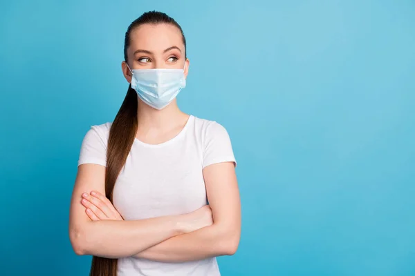 Foto van zelfbewuste dame armen gekruist kijken kant lege ruimte geïnteresseerd lastige uitdrukking dragen beschermen gezicht medisch masker wit t-shirt geïsoleerde blauwe kleur achtergrond — Stockfoto