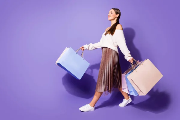 Full length profile side photo of positive satisfied girl enjoy shopping go walk copyspace store mall hold many bags wear brown sweater footwear isolated purple color background — Stock Photo, Image