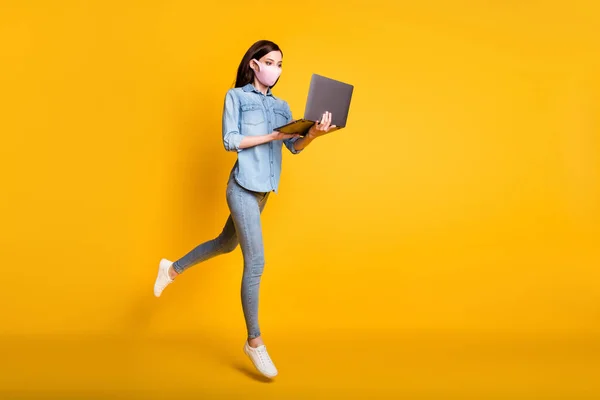 Pełne ciało zdjęcie skoncentrowany ceo dziewczyna skok praca zdalny laptop zegarek seminarium szkolenie połączenie nosić medyczna maska moda styl życia dżinsy koszula odizolowany żółty kolor tło — Zdjęcie stockowe