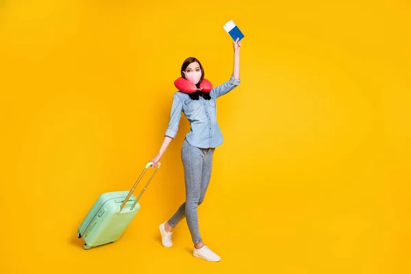 Full length profile side photo student girl hold tickets bag luggage travel foreign go check-in wear medical mask μαλακό μαξιλάρι λαιμού τζιν πουκάμισο απομονωμένο κίτρινο χρώμα φόντο — Φωτογραφία Αρχείου