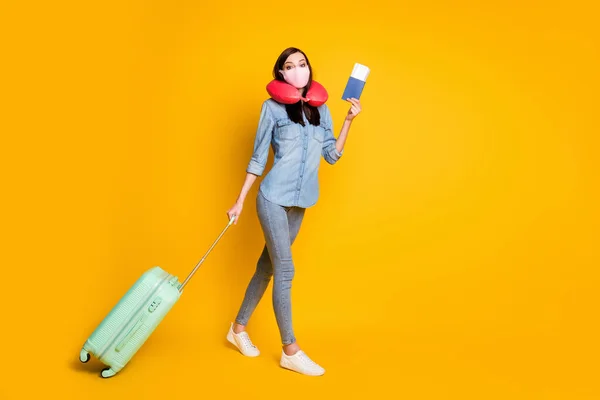 Perfil de corpo inteiro lado positivo estudante menina segurar documentos saco bagagem viagem pronta ir check-in desgaste máscara médica pescoço macio almofada jeans camisa isolada cor amarela brilhante fundo — Fotografia de Stock