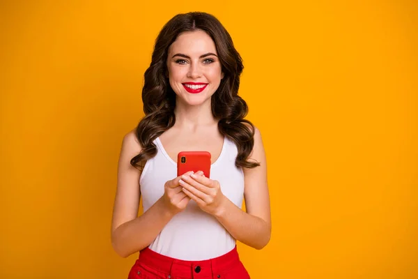 Photo of pretty funny lady hold telephone hands read blog comments good mood check new followers wear casual white singlet red skirt isolated bright yellow color background