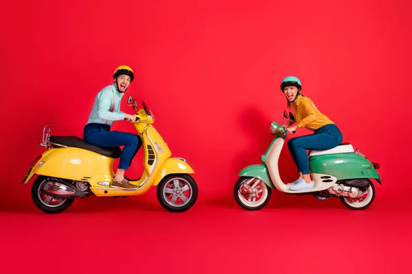 Profiel kant uitzicht van mooie aantrekkelijke gekke extatische dolblij vrolijk paar rijden bromfiets tegenover het hebben van plezier rivaliteit geïsoleerd op heldere levendige glans levendige rode kleur achtergrond — Stockfoto