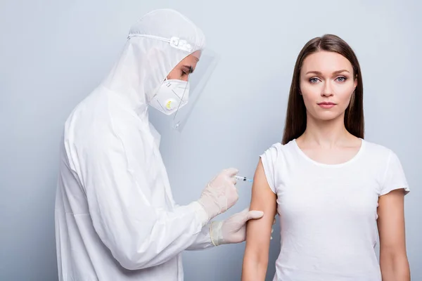 Foto de joven paciente enfermo señora chico experto doc virología inyectar hombro covid antídoto experimental vacuna desgaste máscara capucha uniforme plástico facial protección aislado gris color fondo — Foto de Stock