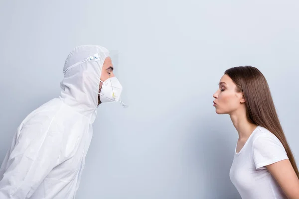 Geen kusjes, geen knuffels. Profiel foto van patiënt dame man doc virologie kliniek paar dates staan tegenover willen kus slijtage masker kap uniform plastic gezichtsbescherming geïsoleerde grijze kleur achtergrond — Stockfoto