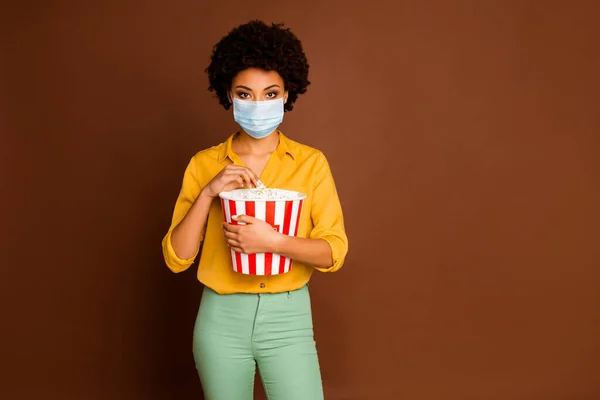 Portrait von ihr sie ziemlich dunkle Haut wellige Dame trägt Mullmaske verbringen Freizeit essen Mais 3d Unterhaltung Freizeit Krankheitsprävention isoliert braune Farbe Hintergrund — Stockfoto