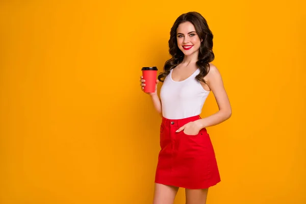 Photo of funny pretty lady hold paper cup na wynos gorąca kawa sobota rano trend młodzież wygląda nosić casual biały zbiornik top czerwony mini spódnica odizolowany żywy żółty kolor tło — Zdjęcie stockowe