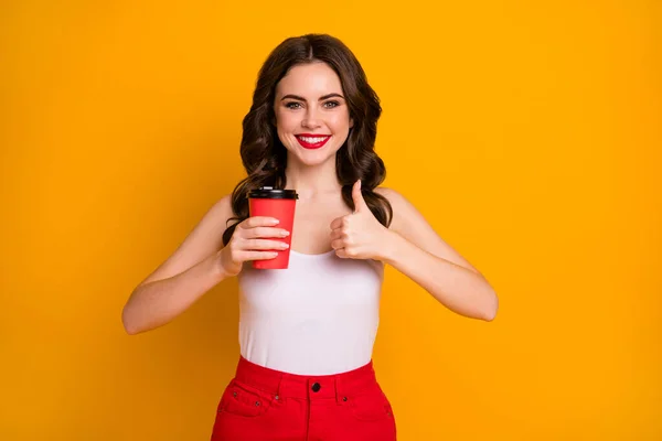 Νόστιμο. Φωτογραφία από αστείο όμορφη κυρία κρατήσει χάρτινο κύπελλο takeaway ζεστό ρόφημα καφέ αυξήσει το δάχτυλο του αντίχειρα επάνω φορούν casual λευκό δεξαμενή κορυφή κόκκινη φούστα απομονωμένο ζωντανό κίτρινο χρώμα φόντο — Φωτογραφία Αρχείου