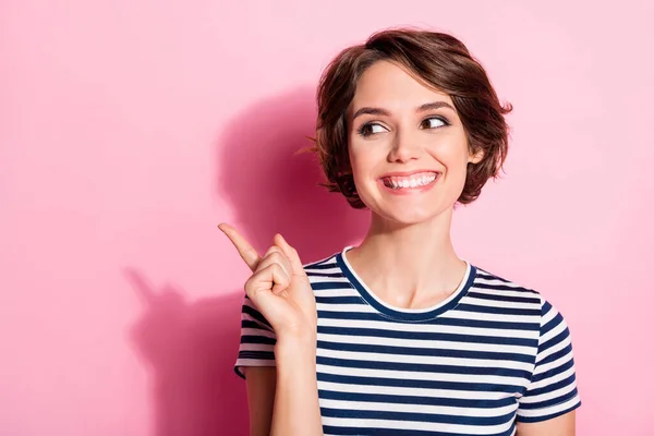 Closeup photo of attractive funny lady look side empty space indicate finger sale prices product banner wear casual white blue t-shirt isolated pastel pink color background