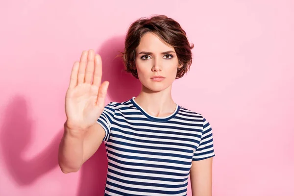 Foto van ernstige humeurige dame houden arm opgeheven stoppen menigte beperken beweging in de richting van het verbod symbool dragen casual wit blauw t-shirt geïsoleerde pastel roze kleur achtergrond — Stockfoto