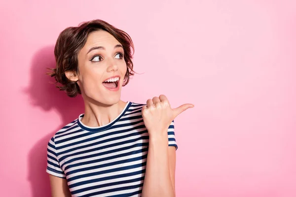 Closeup photo of attractive interested lady clever eyes look side empty space directing finger sale product banner wear casual white blue t-shirt isolated pastel pink color background