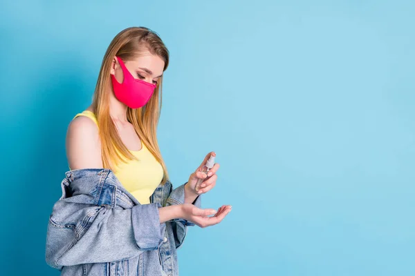 Perfil foto de bela senhora usar bolsa organizador spray anti-séptico desinfetar os braços depois de lotado local social desgaste máscara jeans blazer amarelo tanque top isolado azul cor fundo — Fotografia de Stock