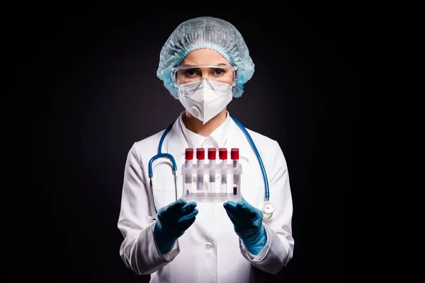 Foto de primer plano de la clínica virología doc mantenga tubos de prueba de sonda de sangre enfermos pacientes que analizan el resultado use bata de laboratorio máscara facial gafas de protección plástica tapa quirúrgica aislado fondo negro — Foto de Stock