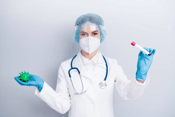 Photo of beautiful lady doc hold covid bacteria blood probe tube analysing infecting process vaccine research wear gloves mask coat facial plastic surgical cap isolated grey color background — Zdjęcie stockowe