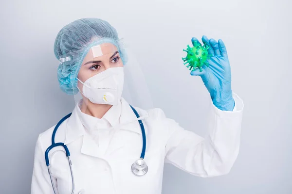 Photo of beautiful lady doc hold covid bacteria simulation analysing infegious process vaccine world research wear gloves mask coat facial plastic surgical cap isolated grey color background — Zdjęcie stockowe