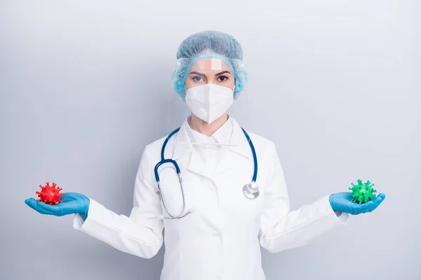 Photo of serious lady doc hold red green covid two bacteria demonstrating mutation process vaccine research wear gloves mask coat facial plastic surgical cap isolated grey color background — Zdjęcie stockowe