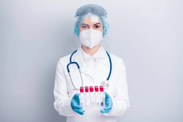 Φωτογραφία του νοσοκόμου της νόσου λοίμωξης κρατήστε έτοιμους καθετήρες αίματος covid ασθενείς εργαστηριακή βοηθός βοηθήσει φορούν παλτό μάσκα προσώπου πλαστική ασπίδα προστασία χειρουργικό κάλυμμα απομονωμένο γκρι φόντο — Φωτογραφία Αρχείου