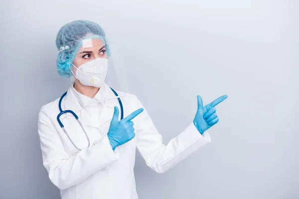 Foto de virologist doc lady diagnosis clinic direct fingers advising vaccination center wear coat respirator mask facial plastic protection surgical hat gloves isolated grey background — Foto de Stock