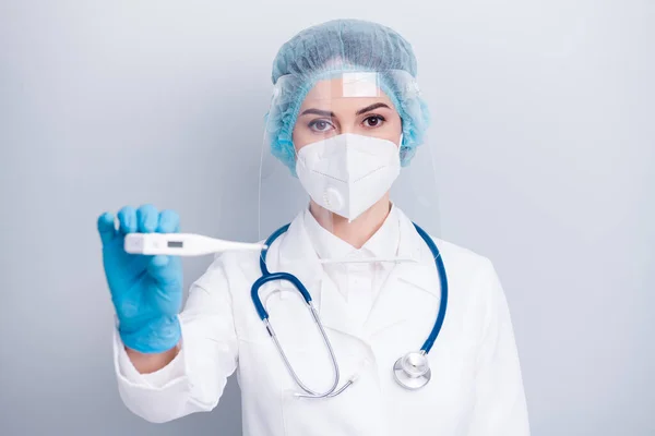 Foto close-up de infecção grave doença virologista médico segurar termômetro controle de fronteira desgaste casaco respirador máscara facial plástico proteção luvas chapéu cirúrgico isolado fundo cinza — Fotografia de Stock