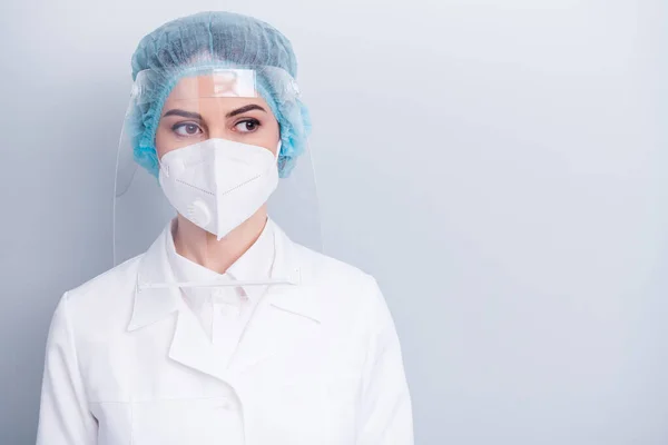 Κοντινό πλάνο φωτογραφία του ελκυστική ιολόγος γιατρός χειρουργική επέμβαση κυρία σώσει τη ζωή ματιά πλευρά ονειροπόληση φορούν ιατρική ρόμπα παλτό μάσκα προσώπου πλαστικό προστασία χειρουργικό καπάκι απομονωμένο γκρι φόντο — Φωτογραφία Αρχείου