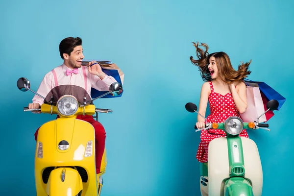 Foto de funky emocionado dama chico pareja unidad alquiler retro ciclomotor viajeros tomados de la mano muchos paquetes de compras buen humor adictos compradores en el extranjero ropa vintage aislado color azul fondo —  Fotos de Stock