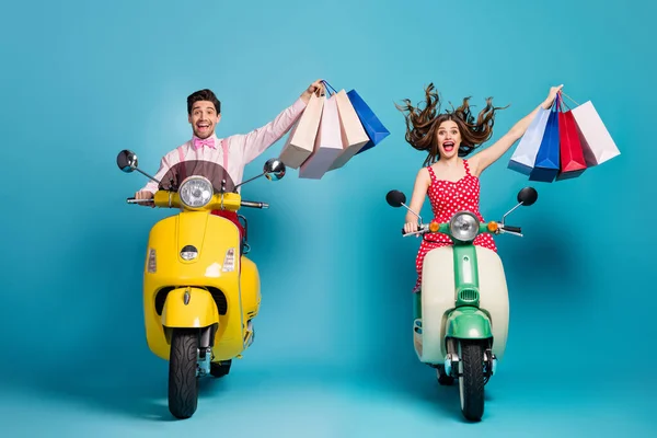 Pełny rozmiar zdjęcie pozytywne dwie osoby mężczyzna kobieta kierowca rowerzysta jazda skuter motocykl centrum handlowe kupić torby cieszyć off-sales nosić czerwony kropkowana sukienka koszulka odizolowany niebieski kolor tło — Zdjęcie stockowe