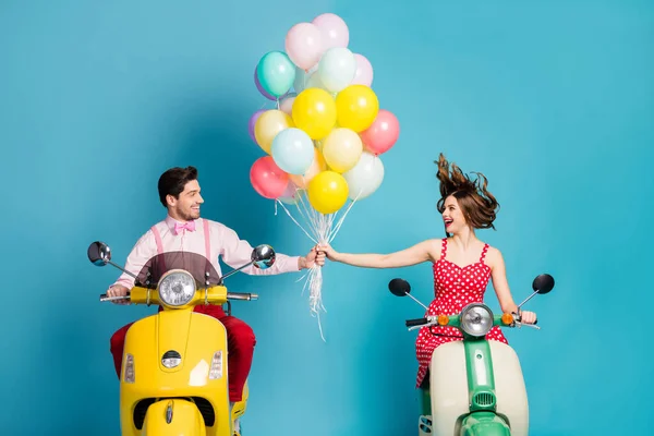 Φωτογραφία από αστεία δύο άτομα κυρία οδηγός ρετρό μοτοποδήλατο ταξιδιώτες κρατούν τα χέρια πολλά μπαλόνια αέρα γενέθλια επισκέπτες καλή διάθεση ρομαντική ατμόσφαιρα vintage ρούχα απομονωμένο μπλε χρώμα φόντο — Φωτογραφία Αρχείου