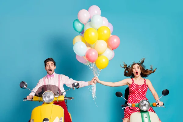 Photo of crazy zszokowany dwóch ludzi pani facet jazdy retro motorowerem podróżników trzymać podnieść ręce wiele balonów urodziny goście latać w górę wiatr vintage ubrania odizolowany niebieski kolor tła — Zdjęcie stockowe