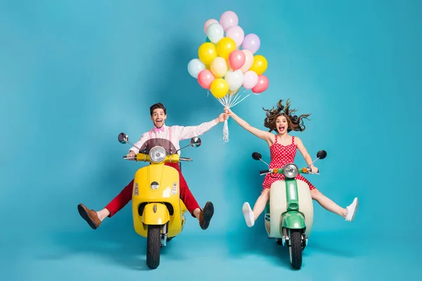 Pleine photo du corps de fou deux personnes dame gars conduire rétro cyclomoteur voyageurs écarter les jambes lever les bras de nombreux ballons d'air anniversaire invités se réjouissant des vêtements vintage isolé fond de couleur bleue — Photo