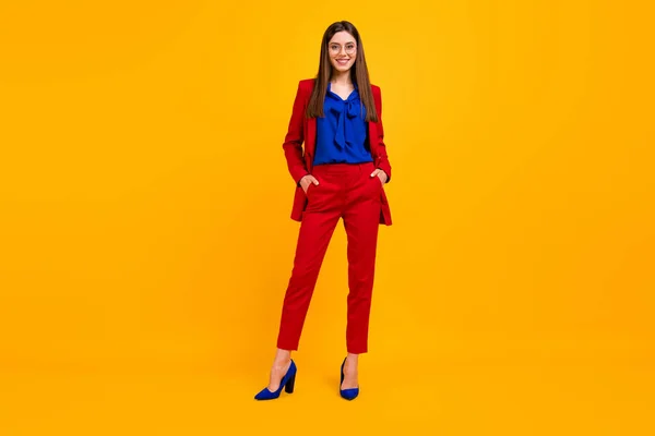 Полное фото тела привлекательной уверенной в себе деловой леди зубастой улыбающейся стоя босс носить очки красный роскошный офис пиджак брюки костюм на высоких каблуках изолированный желтый яркий цвет фона — стоковое фото