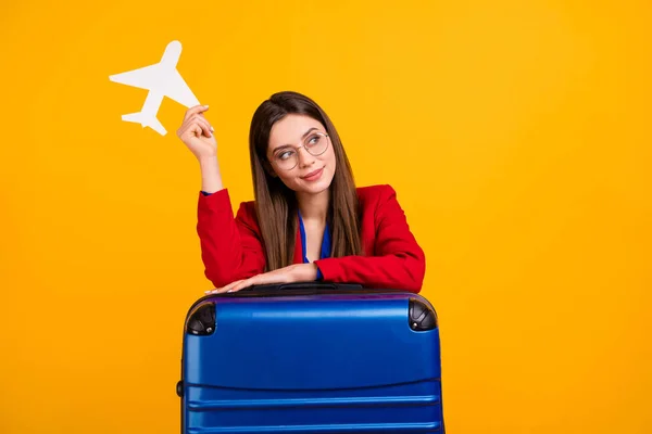 Fénykép az előkelő vonzó üzleti hölgy tartsa papír repülőgép kész nyaralás ferde nagy bőrönd álmodozó viseljen szemüveget piros luxus blézer blúz ruha elszigetelt sárga háttér — Stock Fotó