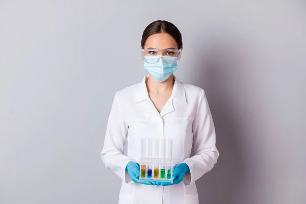 Φωτογραφία της βιολόγου doc κυρία έμπειρος επαγγελματίας κρατήστε δοκιμαστική φιάλη σωληνάρια εξέταση καθετήρες εμβόλιο φορούν γάντια μάσκα προσώπου προστατευτικά γυαλιά ομοιόμορφη εργαστηριακή ποδιά απομονωμένο γκρι φόντο — Φωτογραφία Αρχείου
