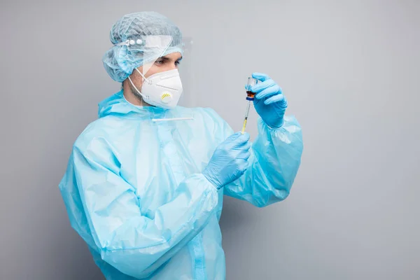 Profiel foto van man expert doc viroloog voor te bereiden tegengif fles injectie genezen zieke patiënt slijtage masker hazmat uniform pak plastic gezichtsbescherming schild geïsoleerde grijze kleur achtergrond — Stockfoto