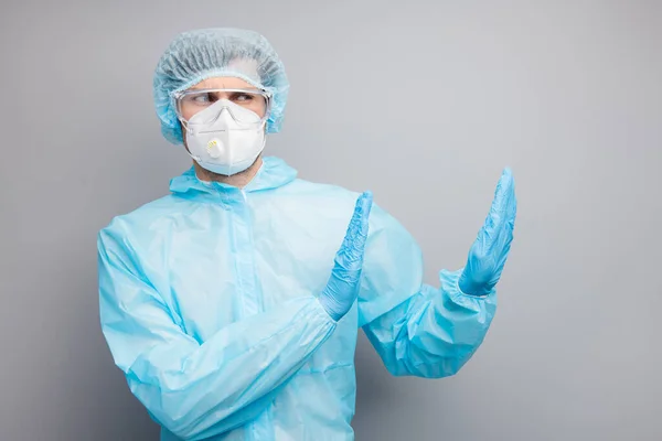 Φωτογραφία του εμπειρογνώμονα doc ιολόγος τύπος αυξήσει τις παλάμες πλευρά άδειο χώρο σταματήσει τους ασθενείς κίνδυνος μολυσμένη ζώνη φορούν γάντια μάσκα Hazmat μπλε ομοιόμορφο χειρουργικό κάλυμμα γυαλιά απομονωμένο γκρι χρώμα φόντο — Φωτογραφία Αρχείου