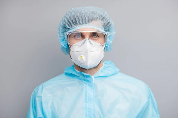 Zbliżenie zdjęcie zabawny facet wirusolog Doc trzymać ramiona na okulary ochronne duże podstępne oczy nosić maskę respirator hazmat niebieski mundur garnitur plastik twarzy gogle izolowane szary kolor tło — Zdjęcie stockowe