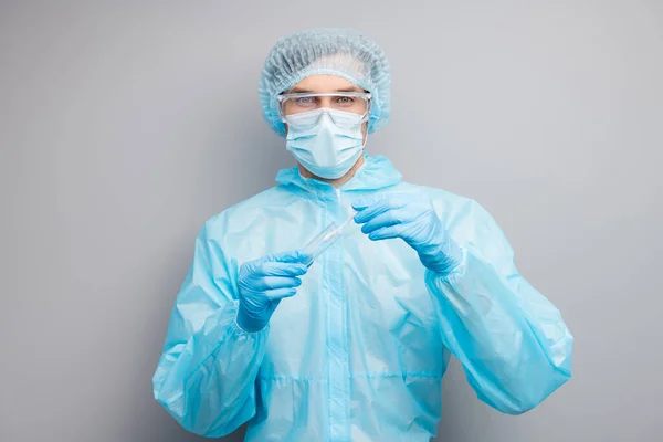 Photo of guy expert doc virolog hold patient ślina sonda rurka covid grypa bakterie badanie kontrolne nosić maskę hazmat niebieski mundur chirurgiczne czapka gogle izolowane szary kolor tła — Zdjęcie stockowe