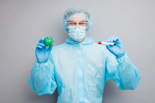 Photo of guy expert virology center hold covid bacteria virus vaccine research blood probe analysis wear mask hazmat uniform surgical cap suit plastic facial goggles isolated grey color background — Zdjęcie stockowe