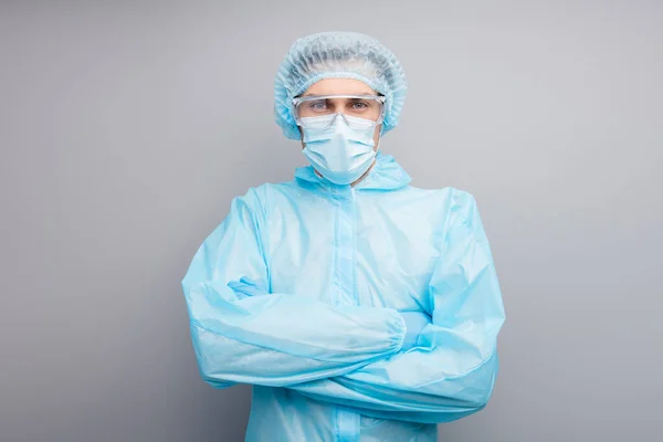 Zdjęcie poważnego faceta ekspert Doc Wirusologia centrum kliniki ramiona skrzyżowane przyszedł zobaczyć covid pacjenta nosić maskę twarzy hazmat niebieski mundur garnitur plastik twarzy gogle izolowane szary kolor tła — Zdjęcie stockowe