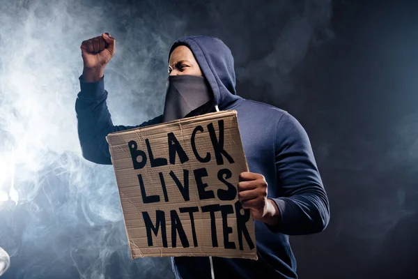 Profil strona zdjęcie szalony afro amerykański facet trzymać sztandar podnieść pięści zachęcić społeczność zatrzymać rasizm izolowane nad mgłą czarny kolor tło — Zdjęcie stockowe