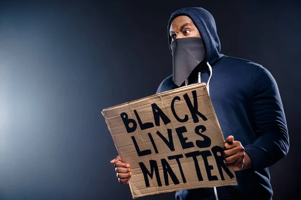 Profile side photo of shocked afro american guy hold banner impresja policja społeczność niesprawiedliwość rasizm problemy nosić sweter sweter odizolowany na czarnym tle — Zdjęcie stockowe