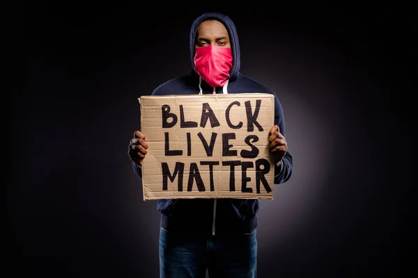 Photo of frustrated afro american guy hold cardboard banner ask start support value human rights wear red bandanna mask jumper isolated over black color background — Stock Photo, Image