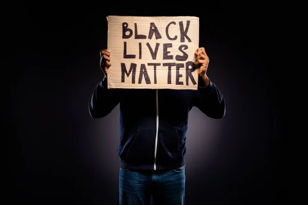 Photo de afro américain guy close cover face cardboard banner démontrer espoir inspirer message pour tolérance humaine porter pull jeans en denim isolé sur fond de couleur noire — Photo