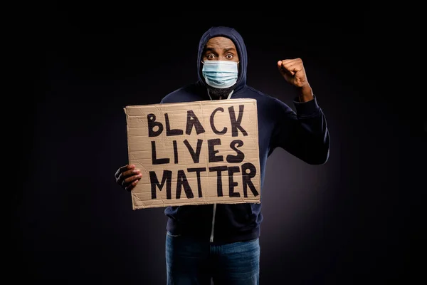 Photo of amazed afro american guy hold cardboard banner black lives banner raise fists celebrate discrimination stop victory hope inspire wear medical mask jumper sweater isolated background — Stock Photo, Image