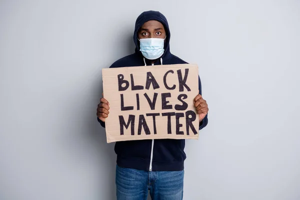 Black lives matter concept. Photo of serious dark skin african poor cold protester placard community against black citizens lawlessness wear hoodie face mask isolated grey color background — Stock Photo, Image