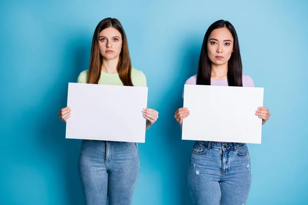 Fotografie vážných dvou lidí dámy lesbičky pár držet zbraně bílé plakáty podporu stejného pohlaví manželství vyjádřit protest oblečení ležérní zelená fialová trička džíny izolované modré barvy pozadí — Stock fotografie