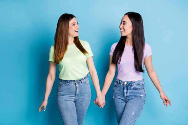 Foto van charmante positieve twee mensen dames lesbiennes paar armen lopen straat chatten beste vrienden fellowship dragen casual groen violet t-shirts jeans geïsoleerde blauwe kleur achtergrond — Stockfoto
