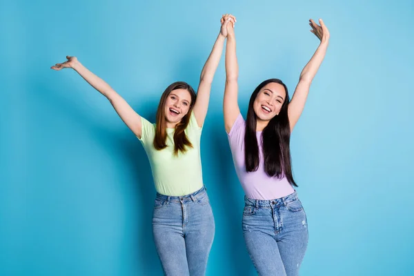 Foto de atraentes senhoras loucas lésbicas casal levantar segurar braços overjoyed educação faculdade colegas primeiro ano estudo desgaste casual t-shirts jeans isolado azul cor fundo — Fotografia de Stock
